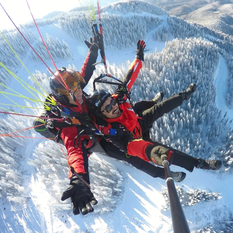 Happy paragliding passenger above Brasov — the perfect gift experience
