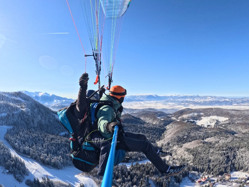Tandem paragliding from Postavaru peak above Poiana Brasov and the Carpathian Mountains